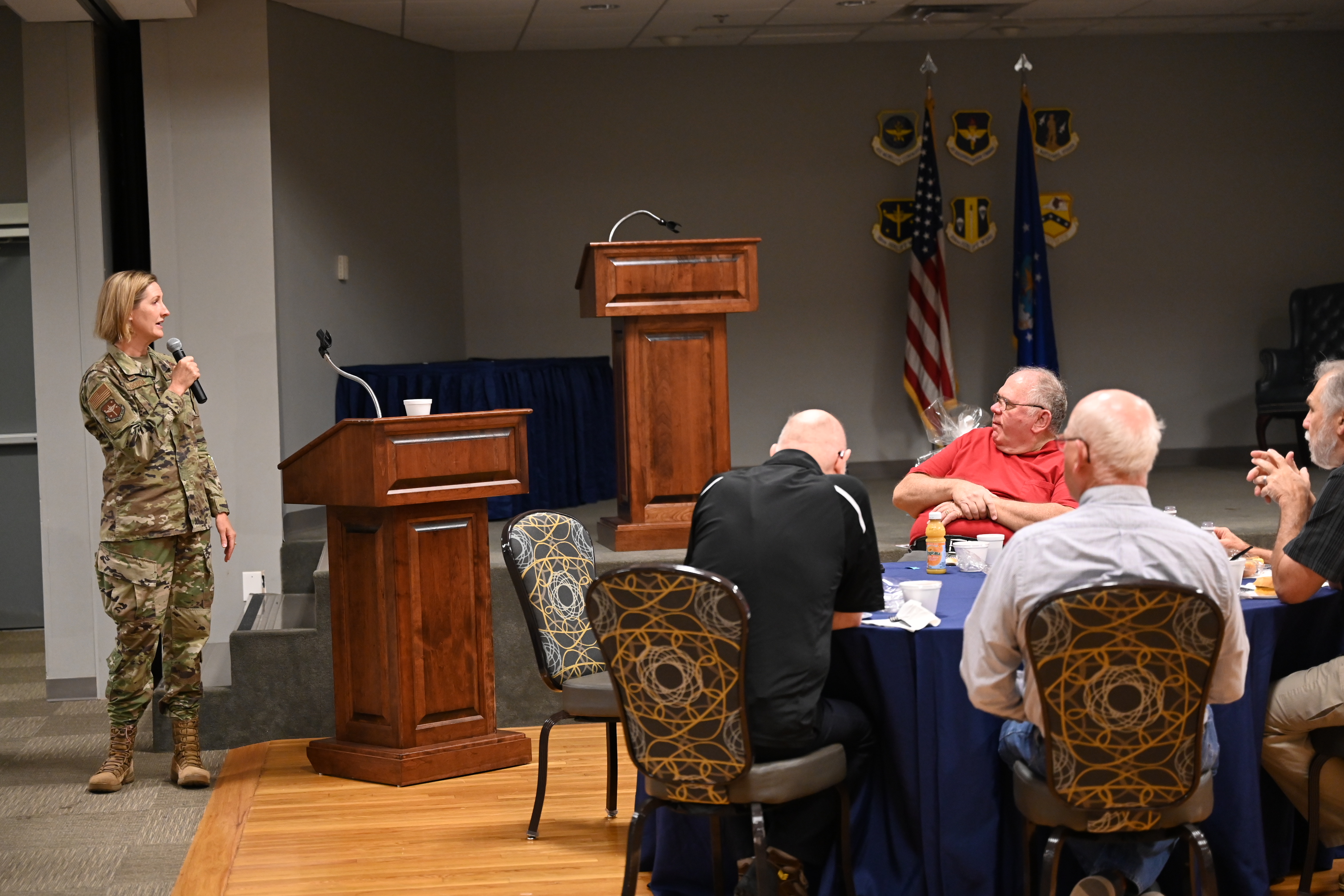 Male Air Force Colonel talks to a crowd of retirees in a restaurant.